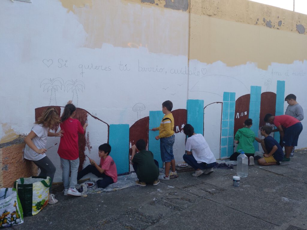 Niños y niñas decorando un muro comunitario
