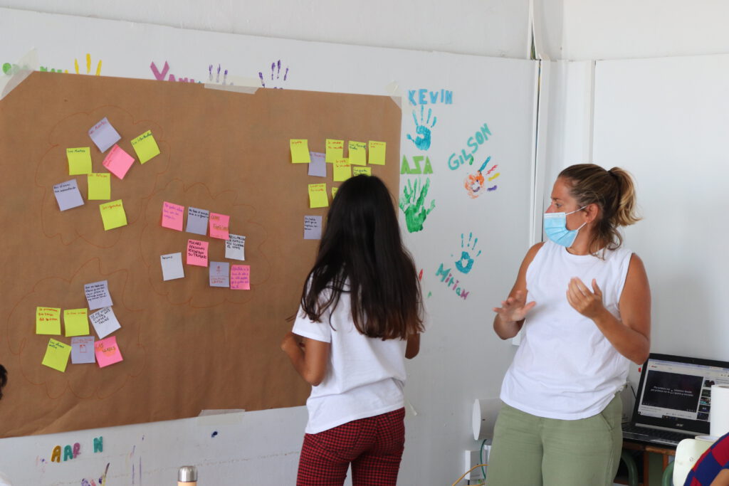 Una mujer y una adolescente mirando un mural en la pared en el que hay post-it de colores pegados